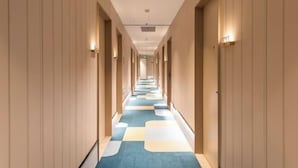 A hotel corridor with wooden paneling, a checkered carpet, and wall-mounted light fixtures. - Beijing Luji Hotel Select (Qinghe High-speed Railway Station Branch) (Beijing)
