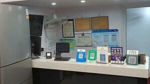 A reception desk with a computer, a fan, and various informational posters. - chezhan hotel (Shanghai)