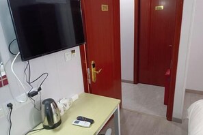 A hotel room with a TV mounted on the wall, a kettle, a remote control, and two doors with room numbers 206 and 205.
