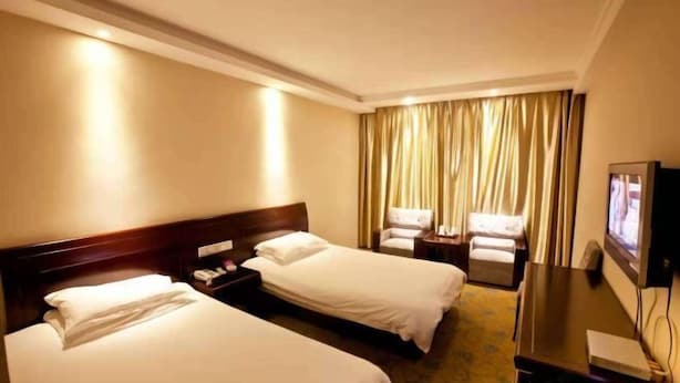 A hotel room with two beds, a TV, a desk, and a chair. - chezhan hotel (Shanghai)