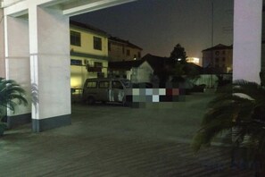 A parking area with a white van, buildings in the background, and a palm tree. - chezhan hotel (Shanghai)