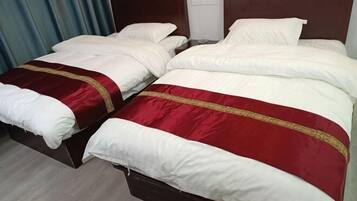 Un lit double avec une literie blanche et rouge, une tête de lit en bois et un plancher en bois.