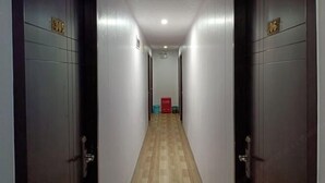 A narrow hallway with two doors on each side, each marked with a number. The floor is wooden, and the walls are light-colored. - chezhan hotel (Shanghai)