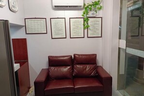 A waiting area with a leather couch, framed documents on the wall, and a potted plant. - chezhan hotel (Shanghai)