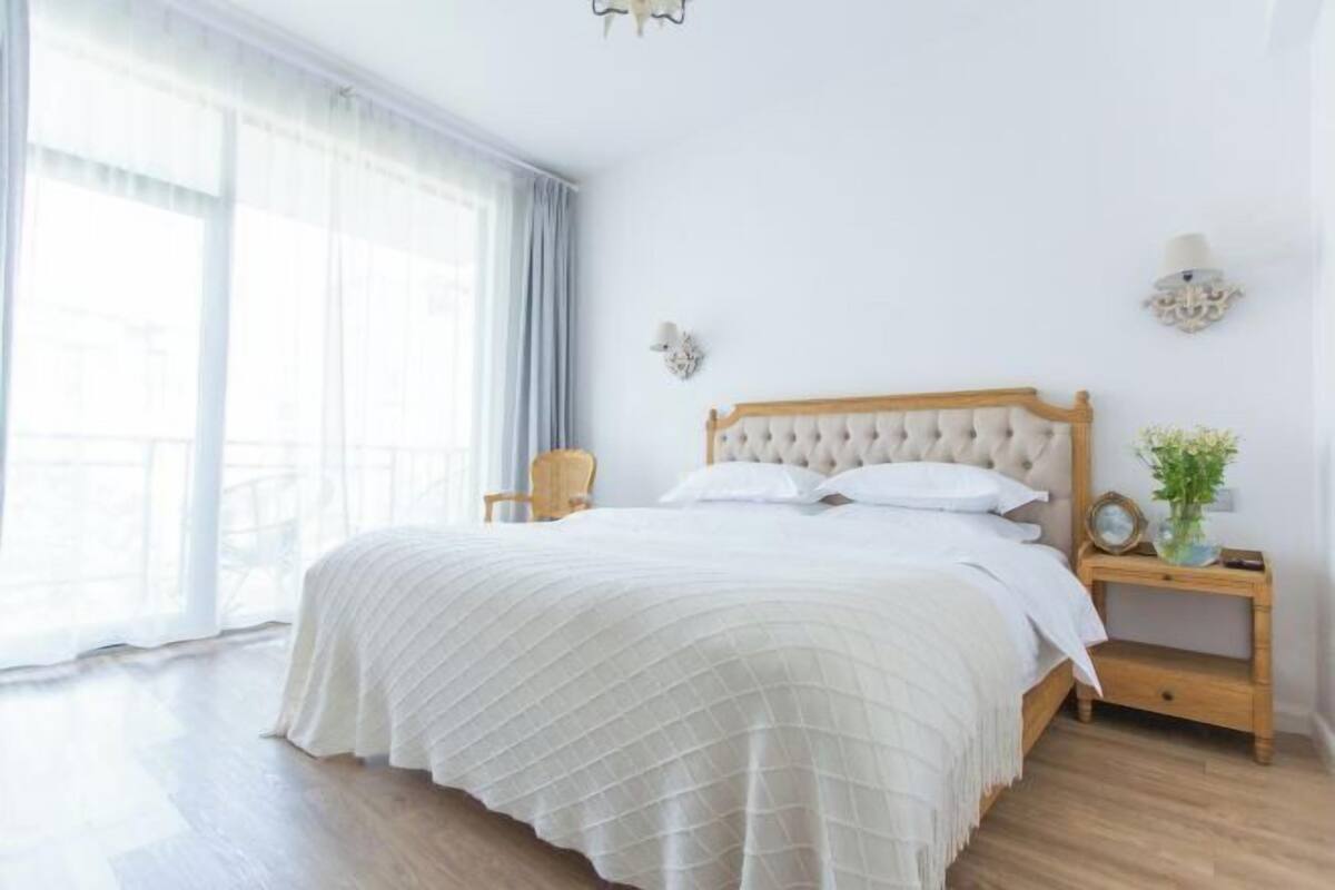 A neatly arranged bedroom with a large bed, a wooden nightstand, and a chair.