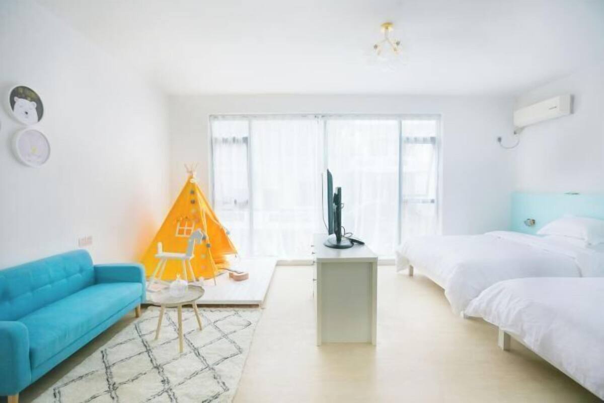 A bright room with a blue sofa, a white bed, and a small table.