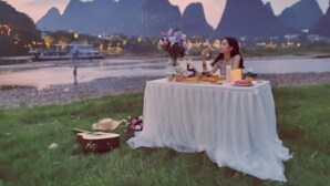 Una mesa al aire libre con mantel, una guitarra y un jarrón de flores.