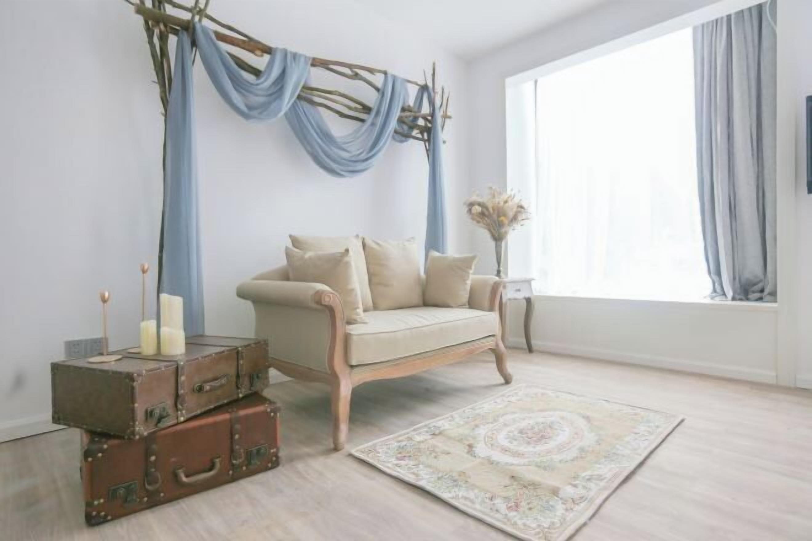 Una habitación con un sofá color beige, un tapete estampado y maletas antiguas.