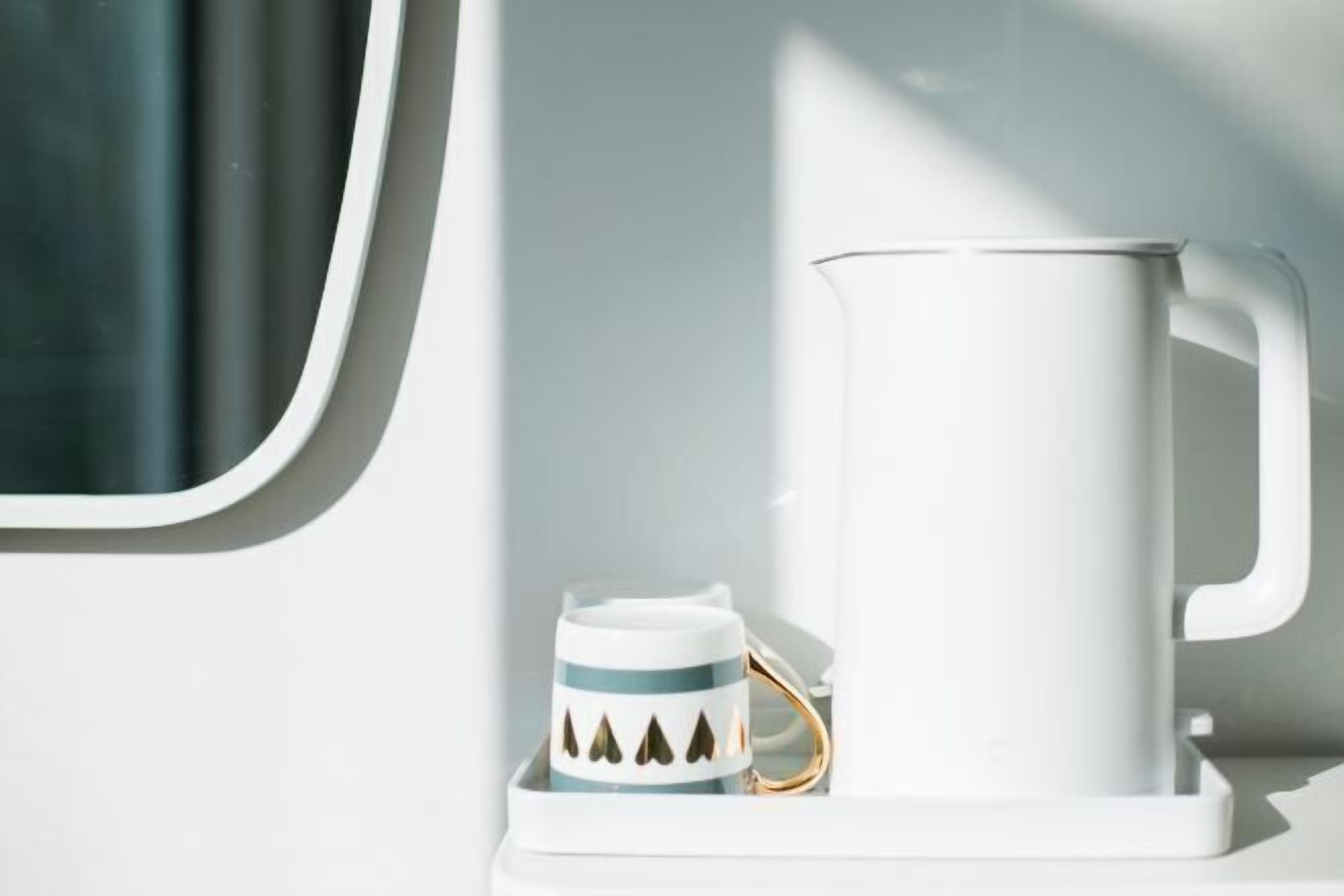 A white mug with a gold handle on a white shelf.