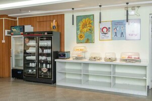Un área de recepción con un expositor de vidrio, un mostrador con alimentos y una pared con carteles.