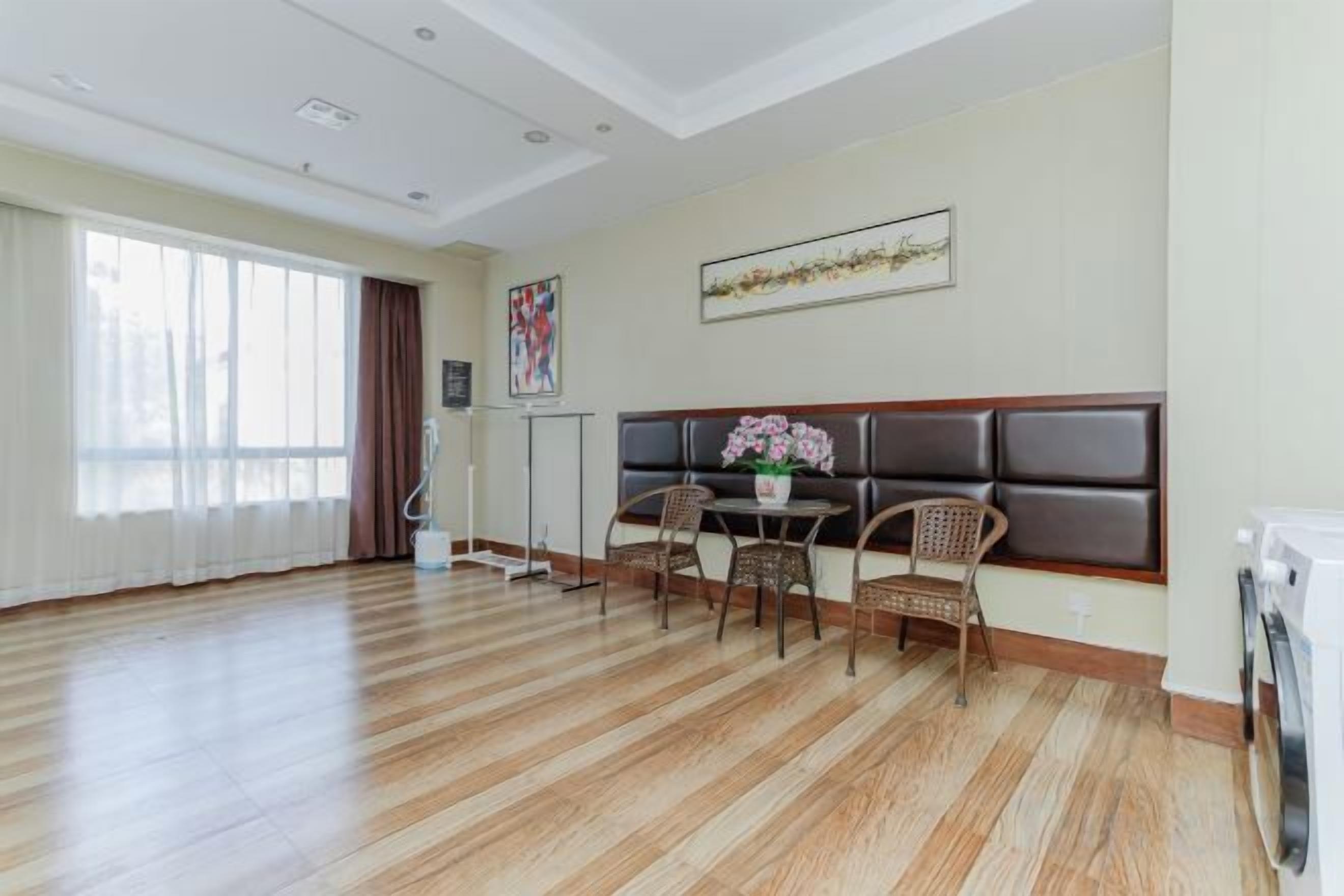 Une pièce avec un plancher en bois, un canapé, une table avec des chaises et une fenêtre avec des rideaux.