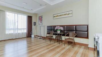 Une pièce avec un plancher en bois, un canapé, une table avec des chaises et une fenêtre avec des rideaux.