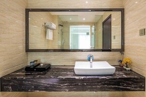 Un baño con encimera de mármol, lavabo blanco y un espejo grande.