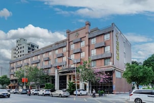 Un hôtel à plusieurs étages, doté d’une entrée imposante, de nombreuses places de stationnement et offrant une vue sur un ciel dégagé.
