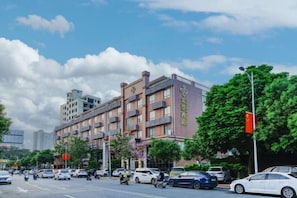 A multi-story hotel with a modern facade, located on a busy street with cars and motorcycles passing by. - Golden Hotel (Sihui)