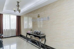 A hotel lobby with a marble wall, a reception desk, and a chandelier. - Golden Hotel (Sihui)