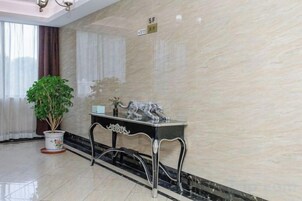 Un vestíbulo con pared de mármol, una planta en maceta, una mesa decorativa y un cartel que indica el nivel del piso.