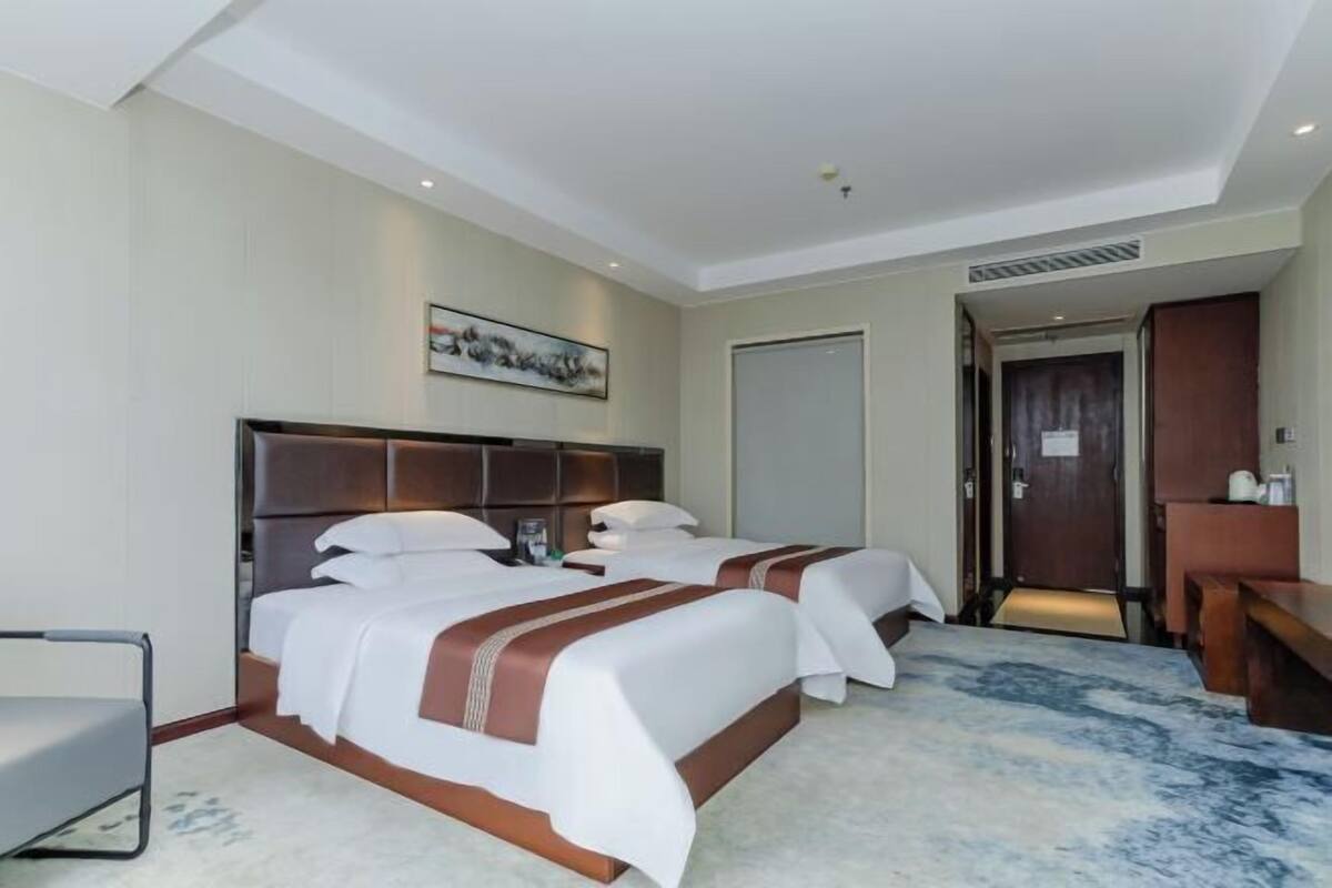 A hotel room with two beds, a desk, and a chair.