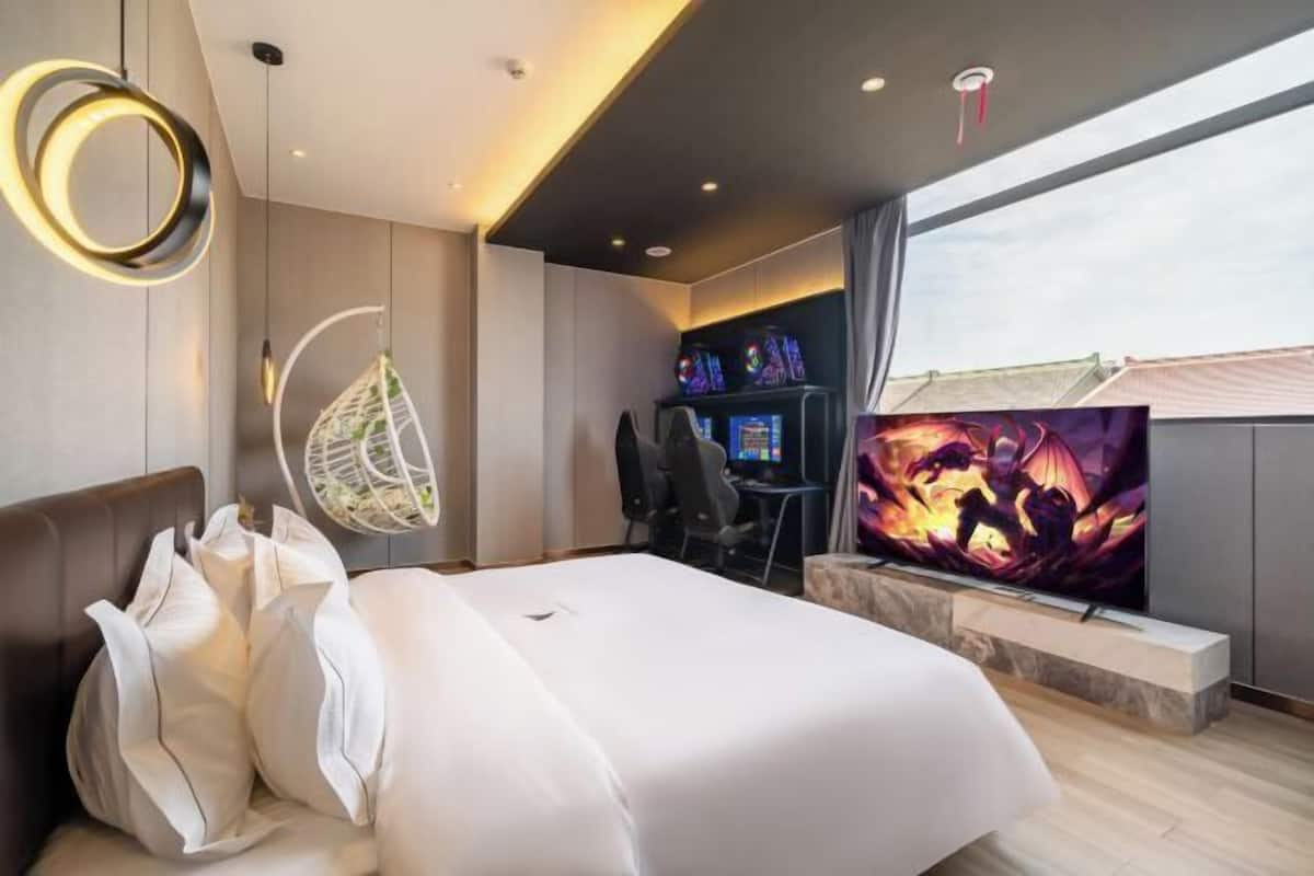 A modern hotel room with a bed, a television, a desk, and a large window.