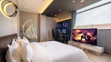 Una habitación de hotel moderna con una cama, un televisor, un escritorio y un ventanal grande.
