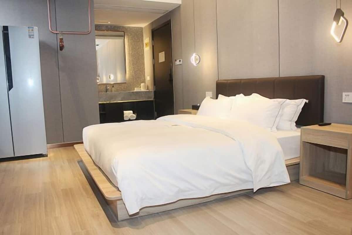 A modern hotel room with a bed, bedside table, and a built-in wardrobe.