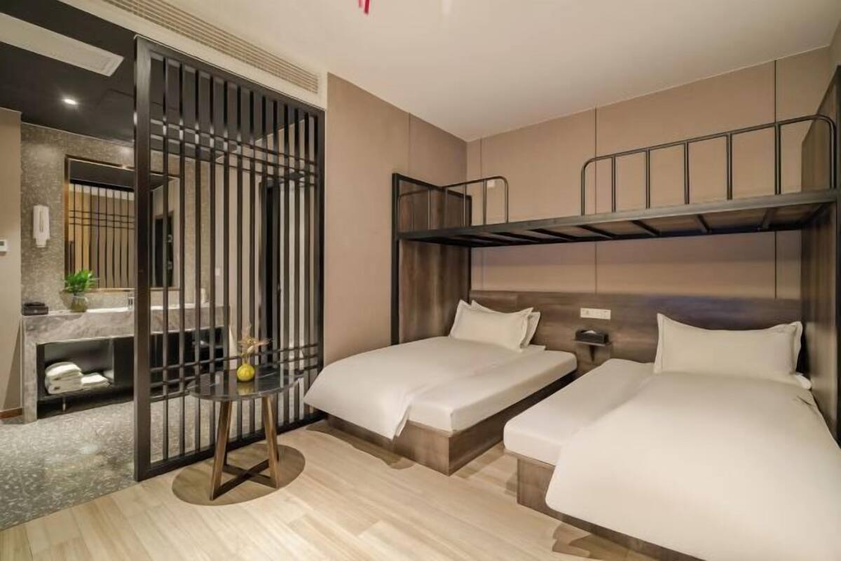 A hotel room with two beds, a small table, and a bathroom area.
