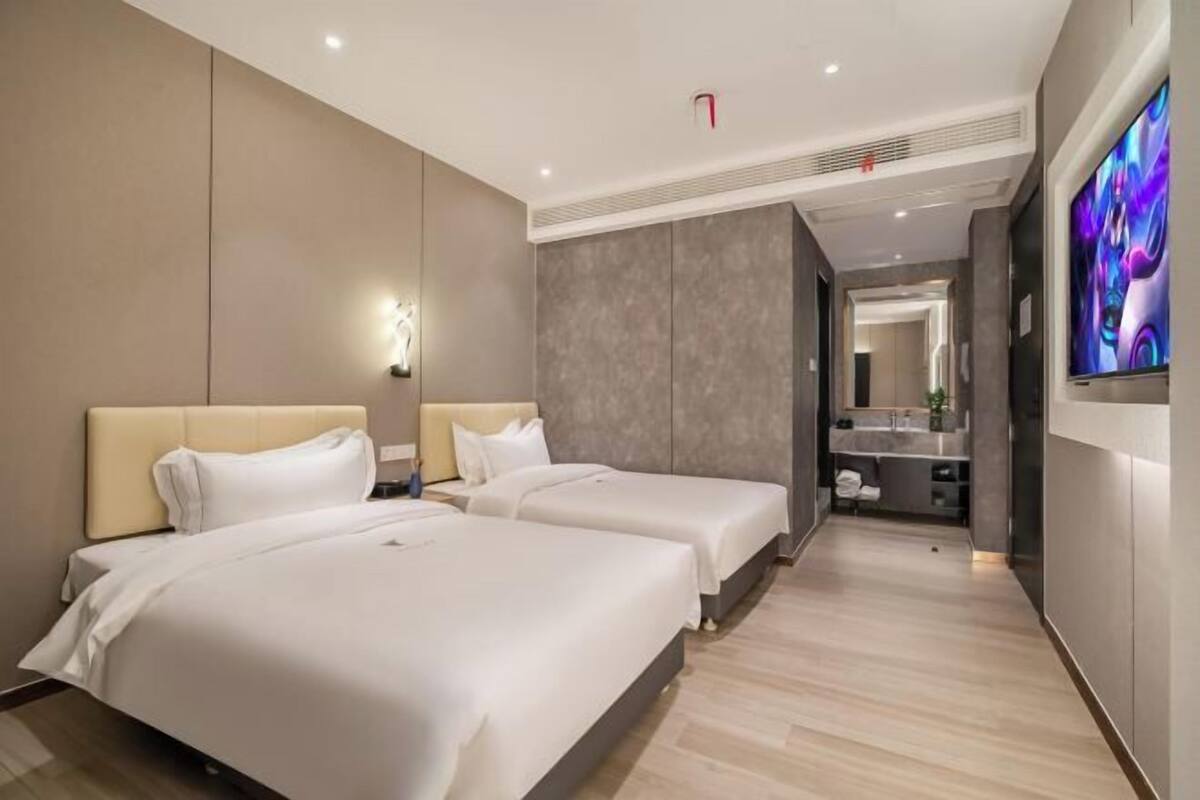 A hotel room with two beds, a bathroom, and a TV.