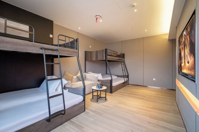 Una habitación de hotel moderna con literas, una mesita pequeña y un cuadro en la pared.