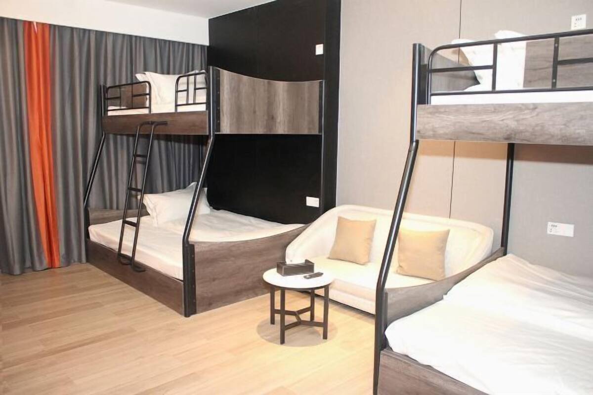 A room with bunk beds, a small table, and a sofa.