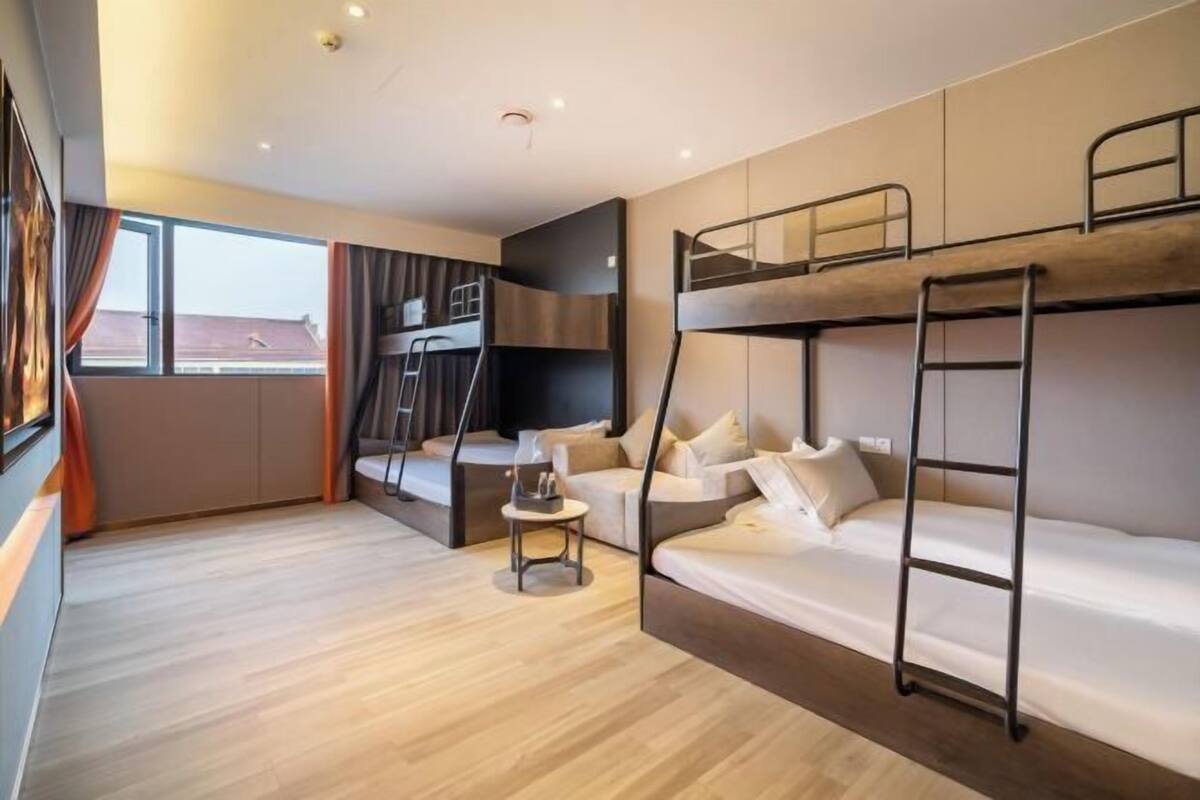 A bunk bed room with a desk and a window.