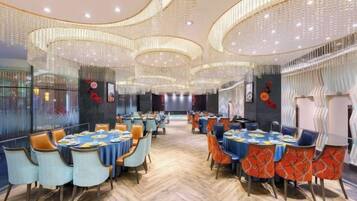 A spacious dining area with round tables, chairs, and a herringbone floor pattern.