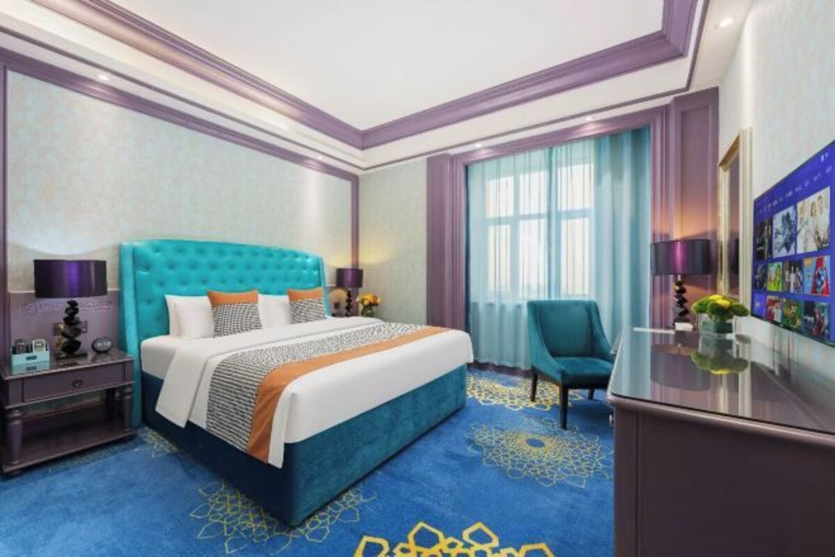 Ein Hotelzimmer mit einem großen Bett, einem Schreibtisch, einem Stuhl und einem Fernseher.