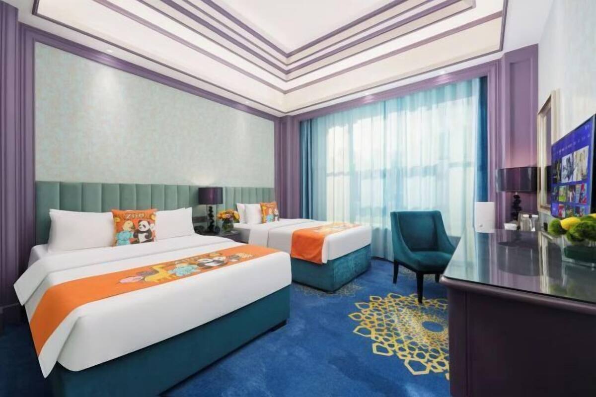 A hotel room with two beds, a desk, and a chair.