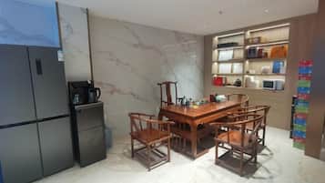 A compact kitchen with a refrigerator, microwave, and a dining table with chairs.
