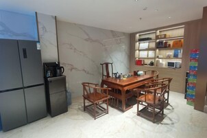 A compact kitchen with a refrigerator, microwave, and a dining table with chairs.