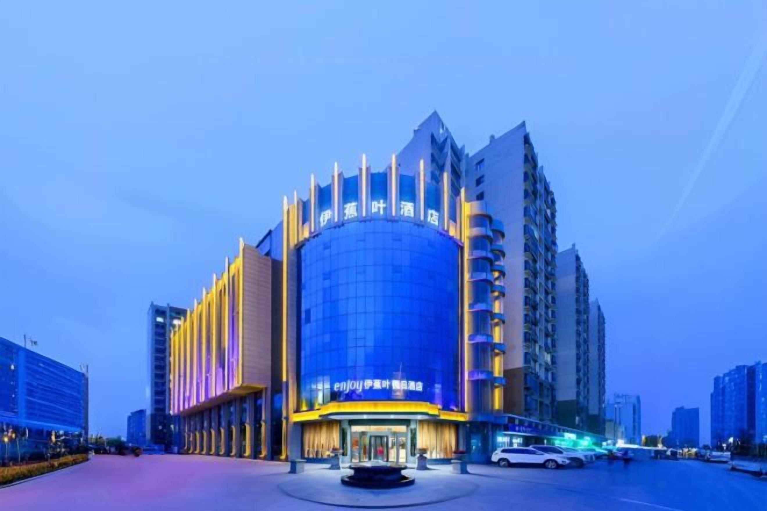A modern hotel with a prominent curved facade, multiple floors, and a central entrance.