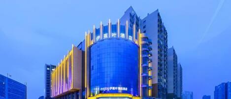 A modern hotel with a prominent curved facade, multiple floors, and a central entrance.
