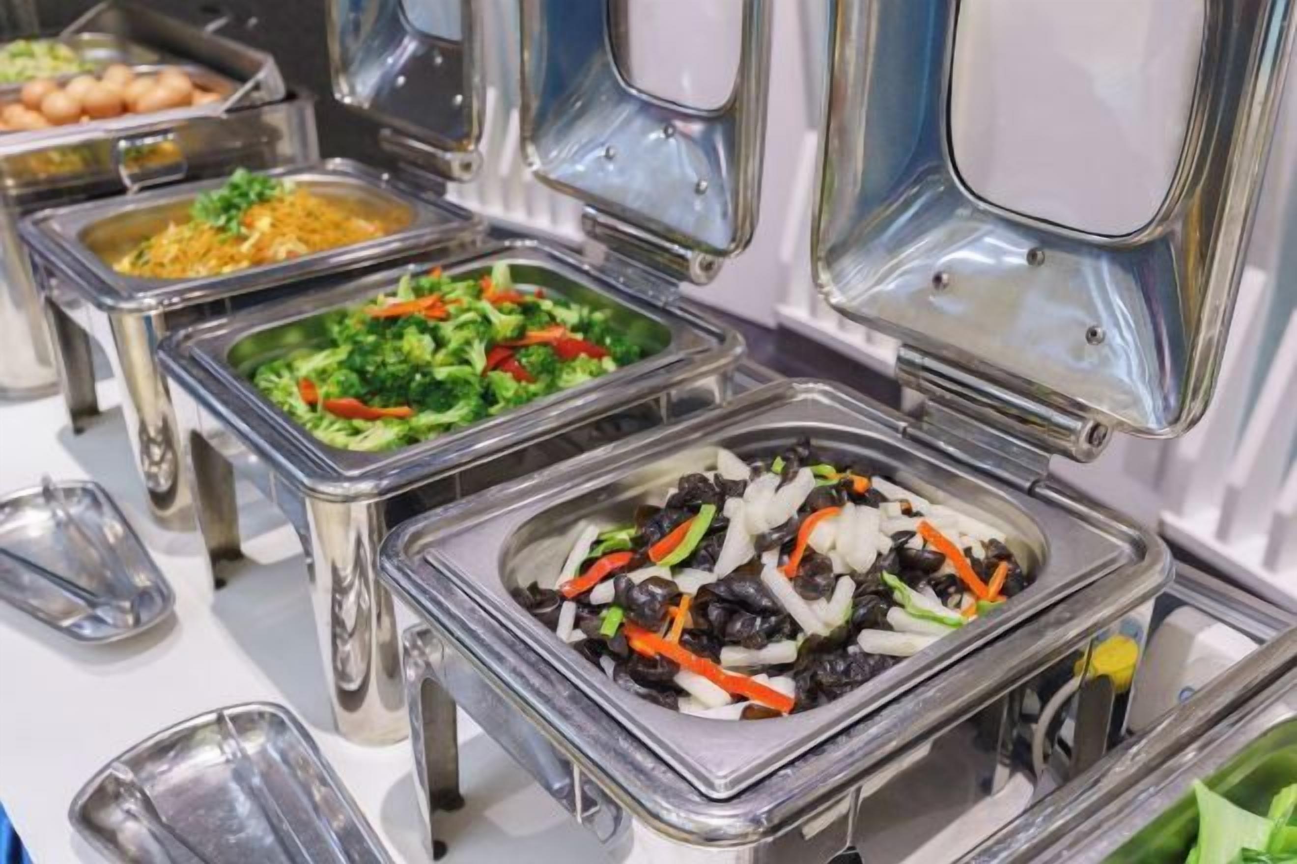 A buffet with various food items in metal serving dishes.