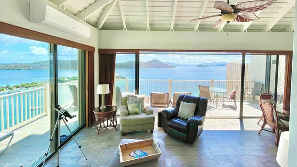 Amplia habitación con balcón grande, un telescopio y un espacio de estar cómodo con vista al mar.