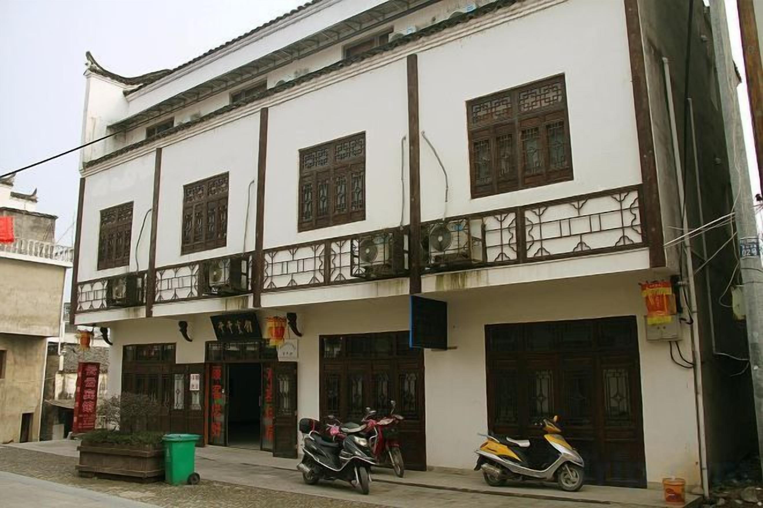 A traditional building with a balcony, multiple doors, and a parked scooter.