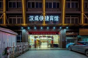 A hotel entrance with a sign in Chinese characters, a gated driveway, and a parked car. - Hancheng Express Hotel (Anqing Railway Station Bus Station) (Anqing)