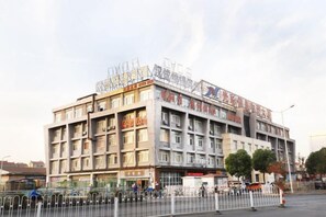 A multi-story building with a commercial ground floor, surrounded by a metal fence. - Hancheng Express Hotel (Anqing Railway Station Bus Station) (Anqing)