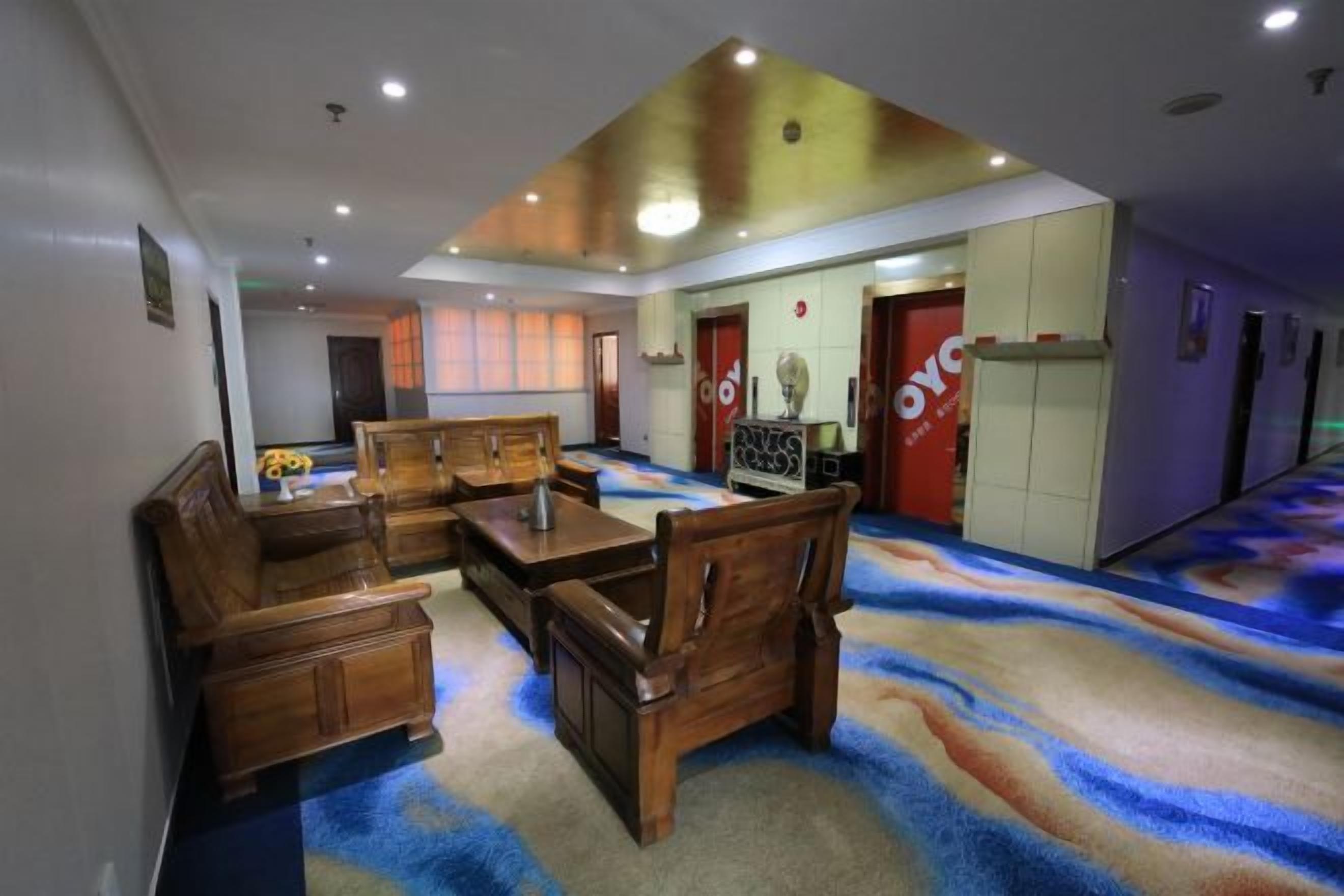 A hotel lobby with a reception desk, seating area, and a carpet with a wave pattern.