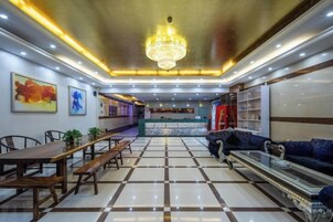 A hotel lobby with a reception desk, seating area, and a chandelier.