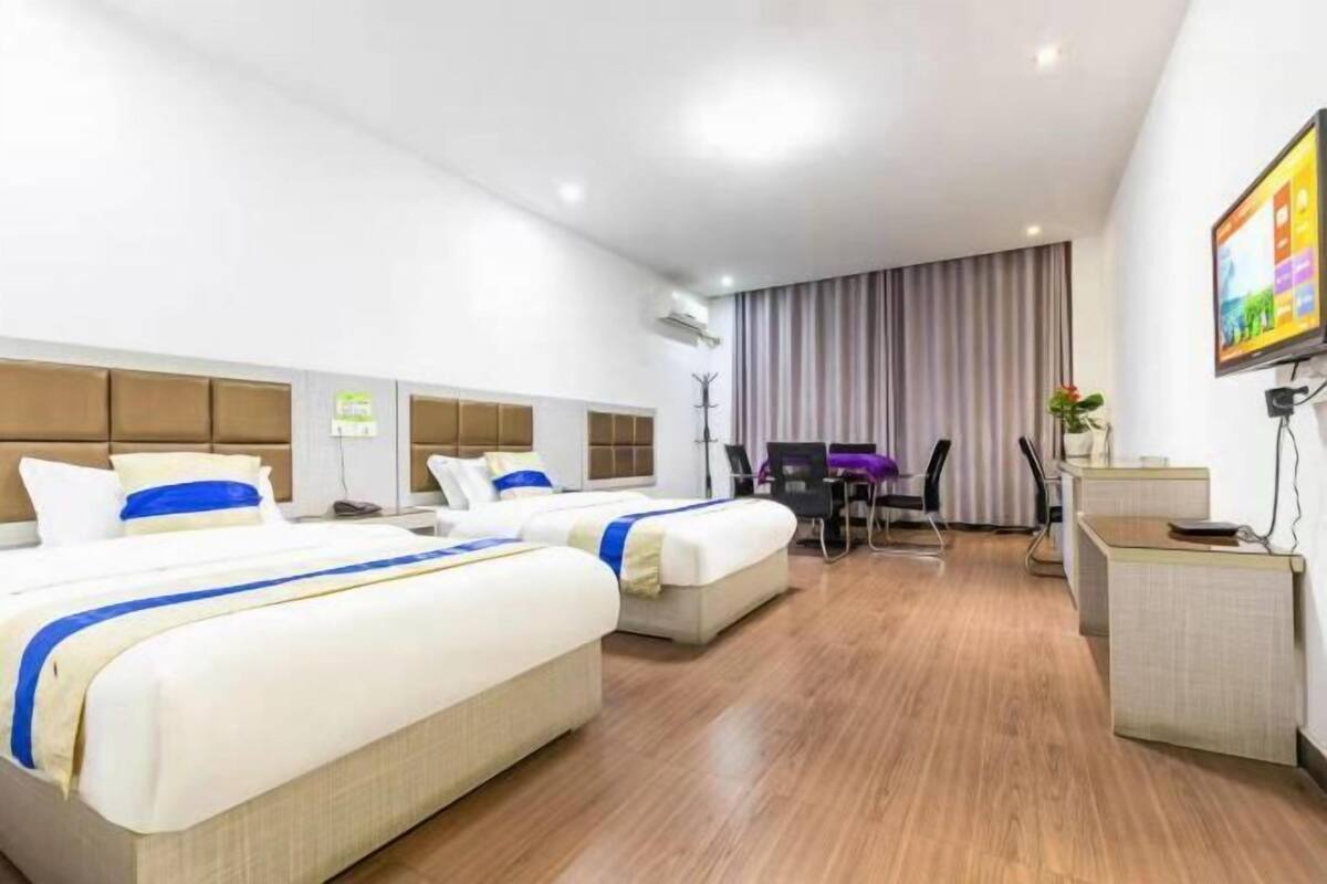 A hotel room with two beds, a desk, a chair, and a TV.