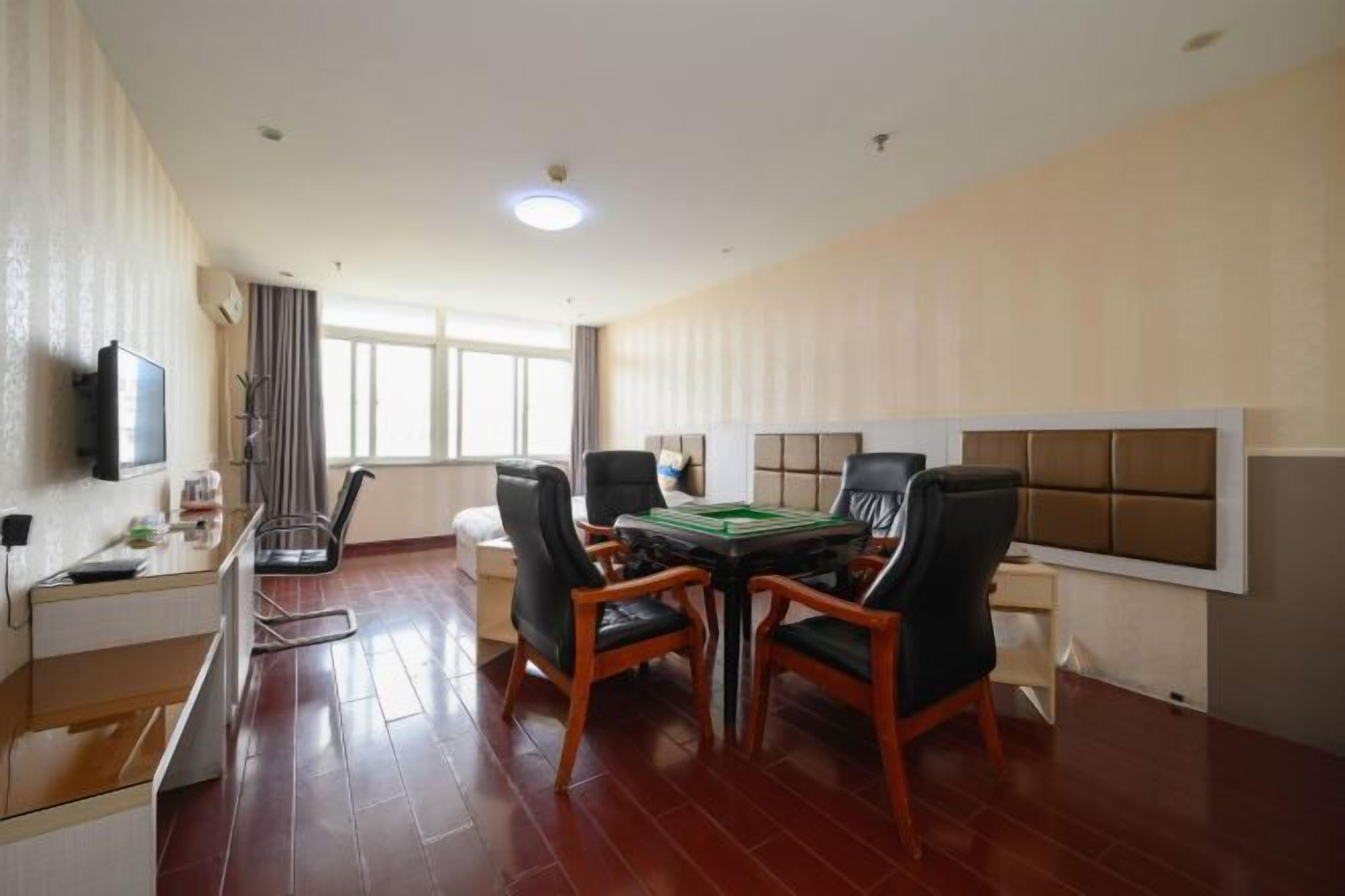 A modern hotel room with a dining area featuring a table and chairs, a television, and a window with curtains.