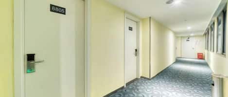 A hallway with doors numbered 8805 and 8806, carpeted with a circular pattern, and a trash bin on the right.