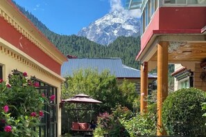 A hotel courtyard with a mountain view, a covered seating area, and a building with traditional architecture. - Meet Snow Mountain Boutique Residence (Bome)