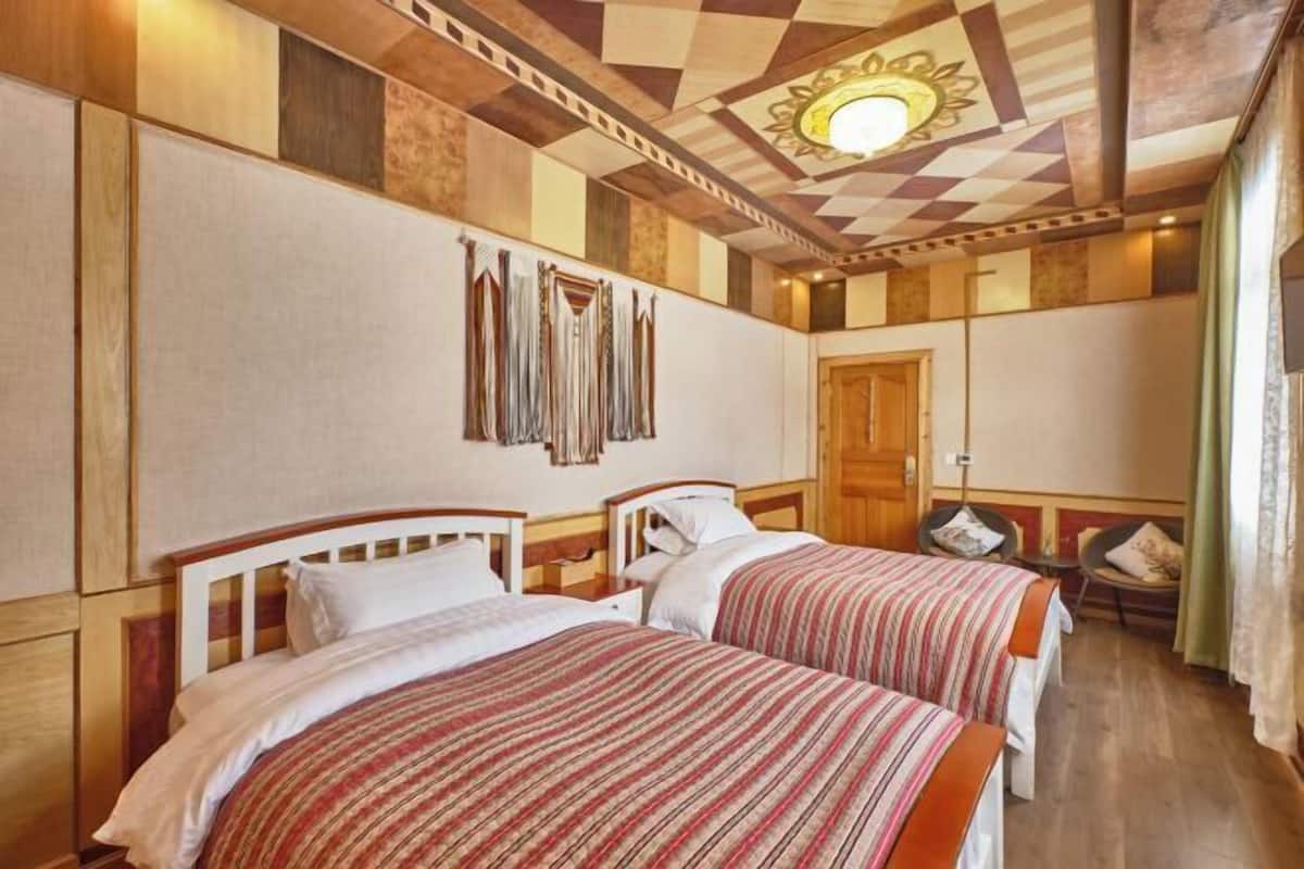 Une chambre d’hôtel avec deux lits, un plafond en bois et un mur orné de motifs.