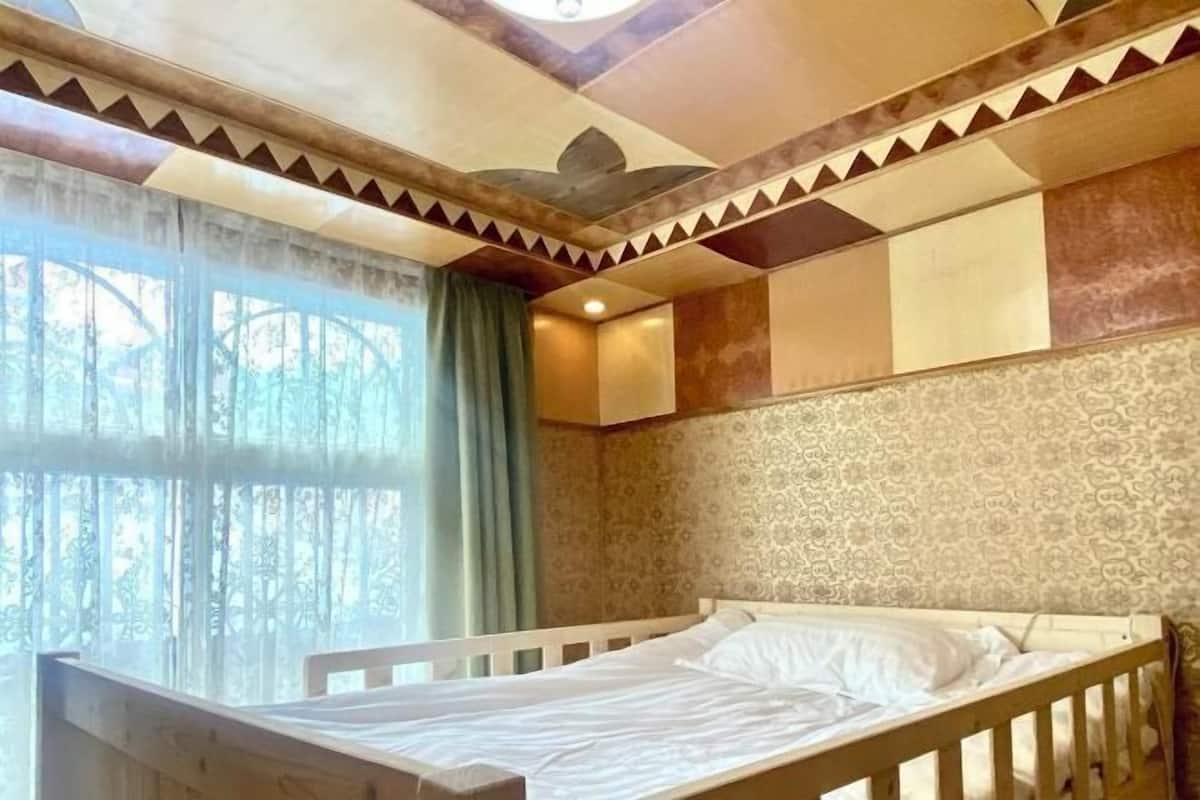 Une pièce avec un lit, un papier peint à motifs et une fenêtre avec des rideaux.